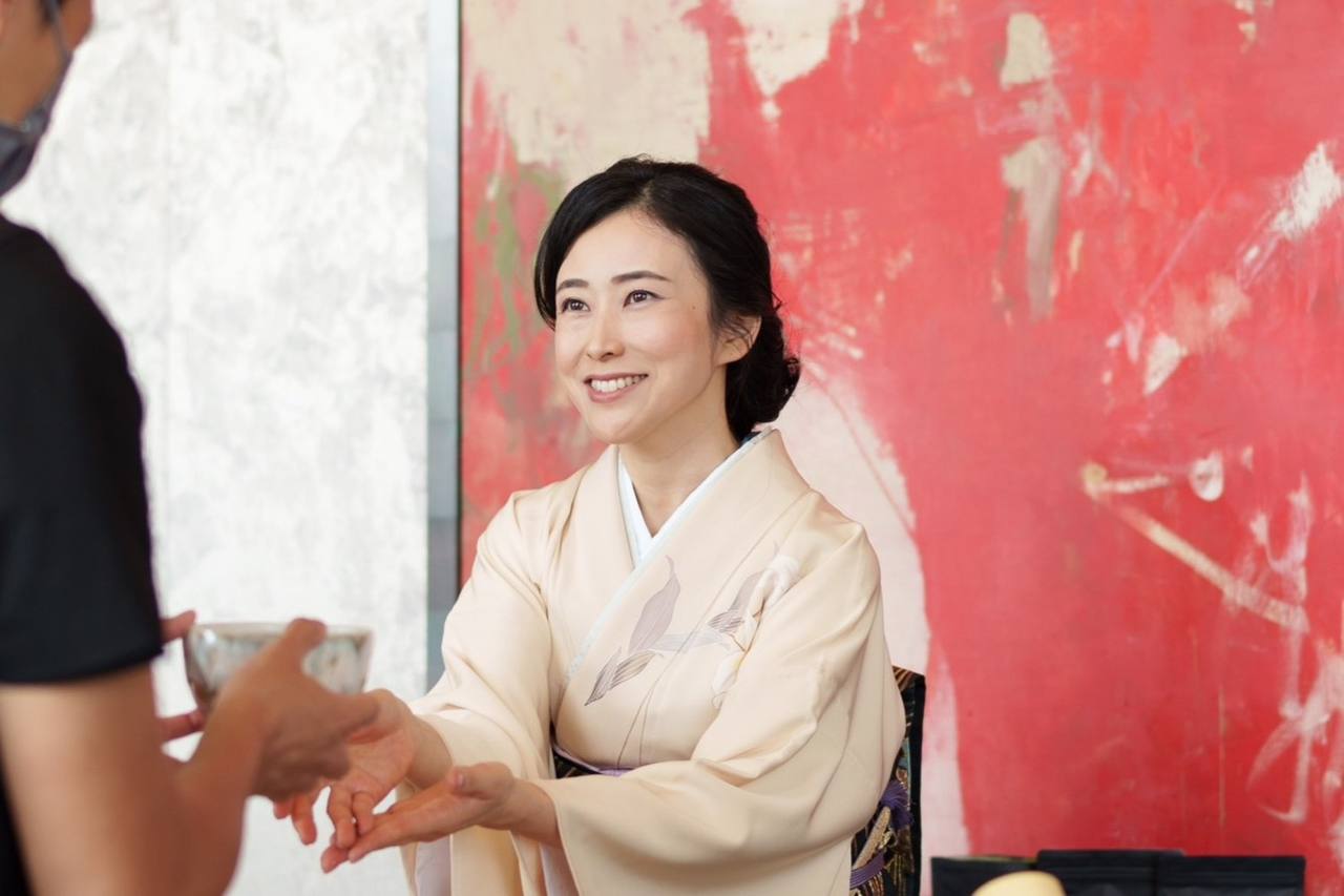 着物姿の神山ナオミさんが、抹茶の茶碗を介して相手と向き合っている場面。
